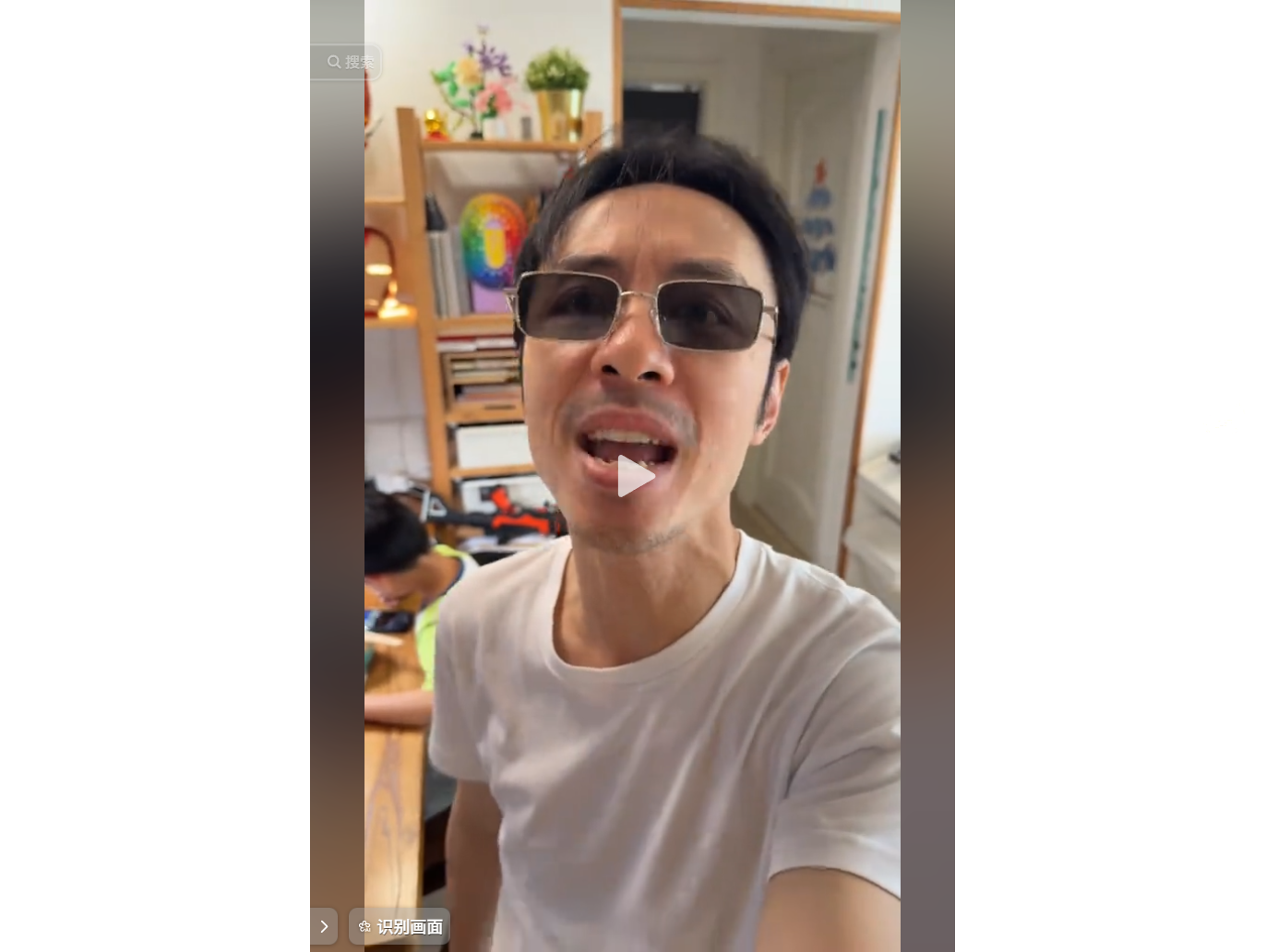 戴墨镜的男子在室内自拍，背景有书架和孩子