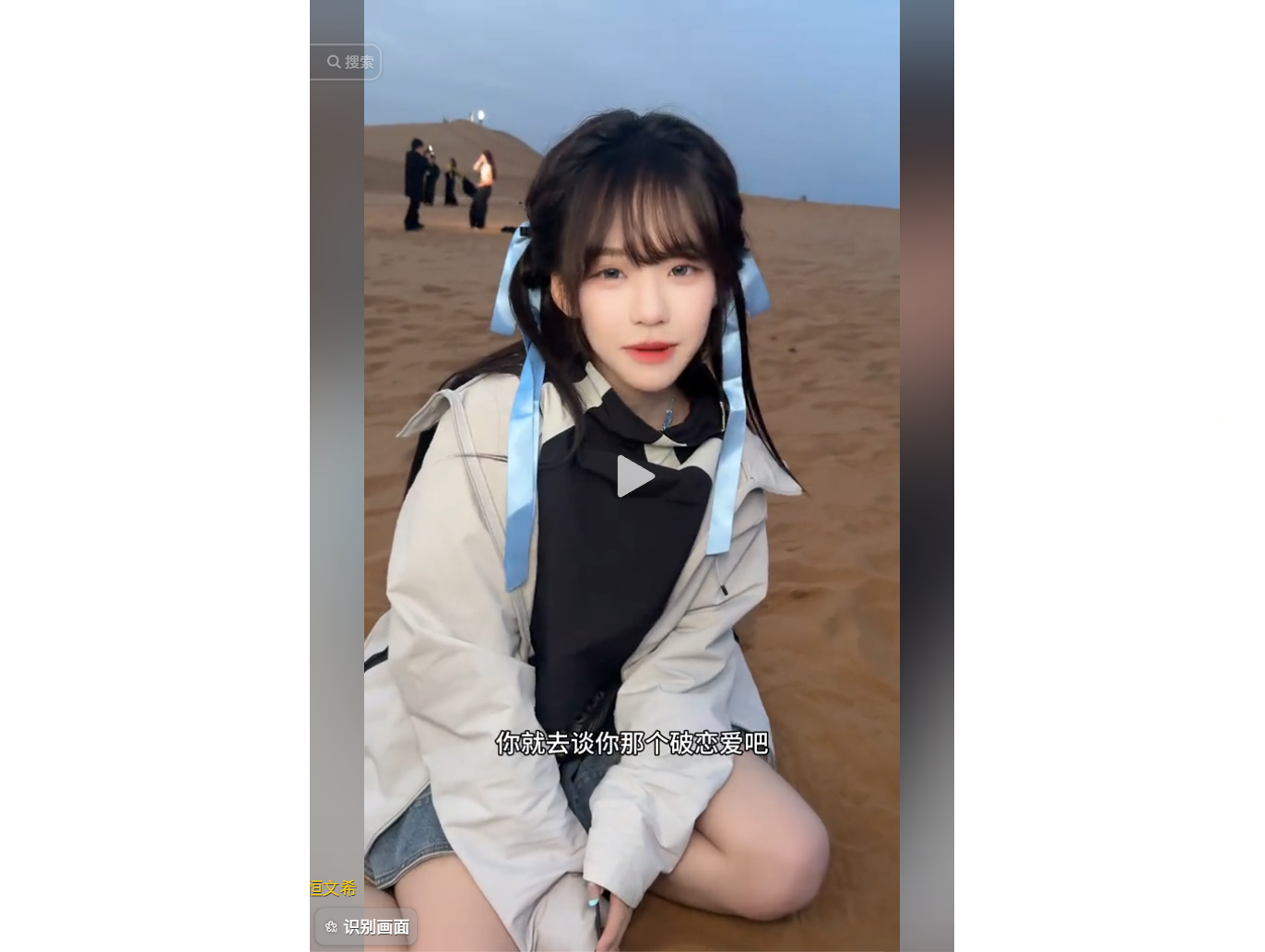 女孩在沙漠中蹲坐，身穿浅色外套和蓝色蝴蝶结发带，背景有几个人影。