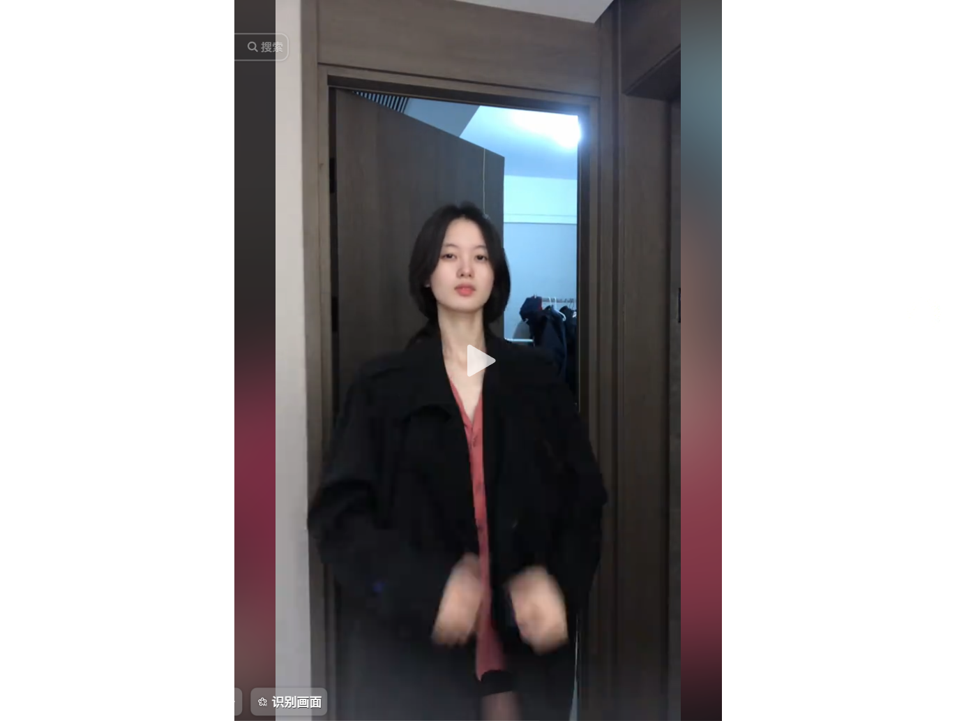 一位年轻女性站在门口，身穿黑色外套和红色内搭，正在整理衣物。