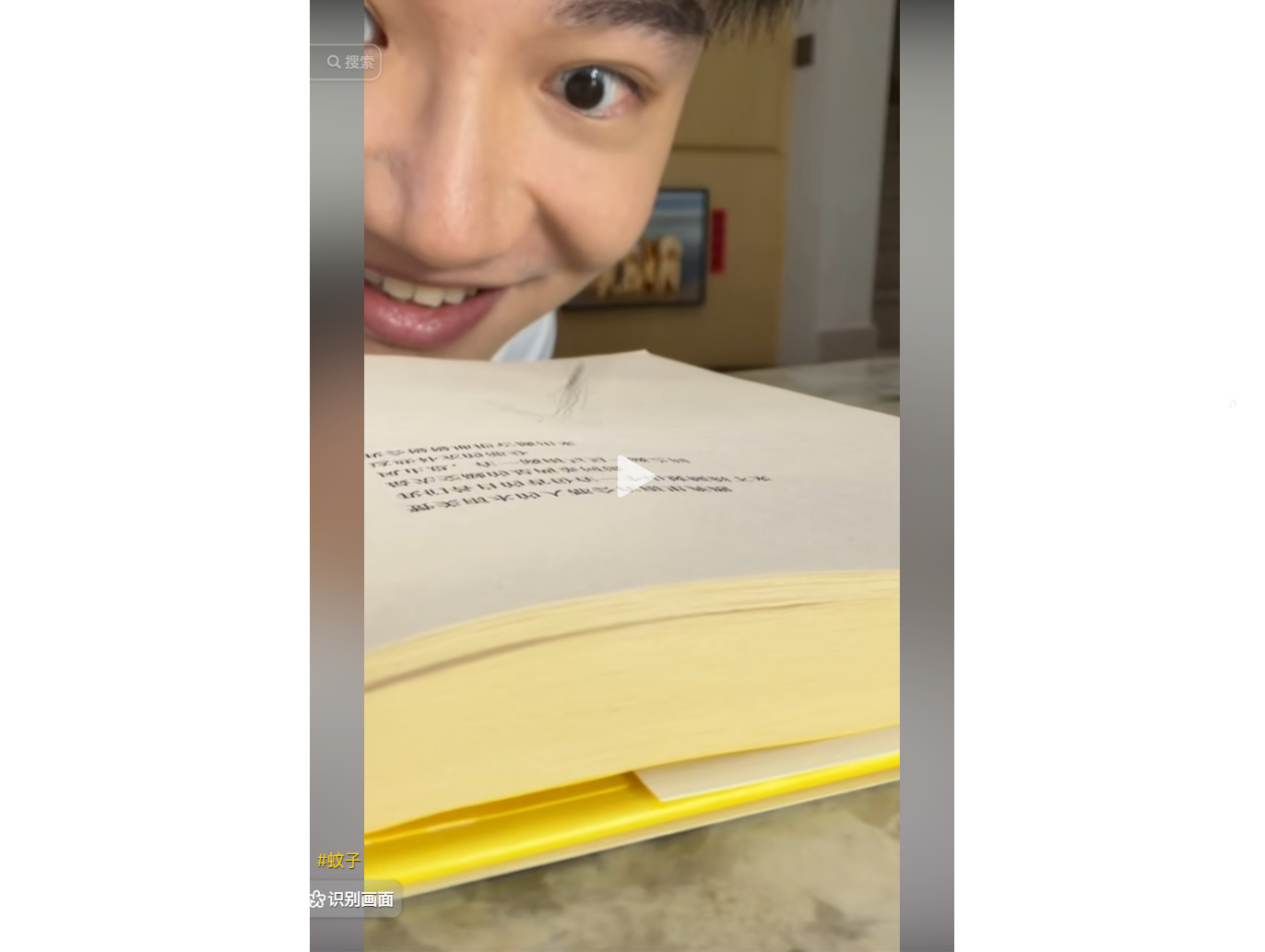 男孩微笑展示一本打開的書籍,書頁上有中文文字。
