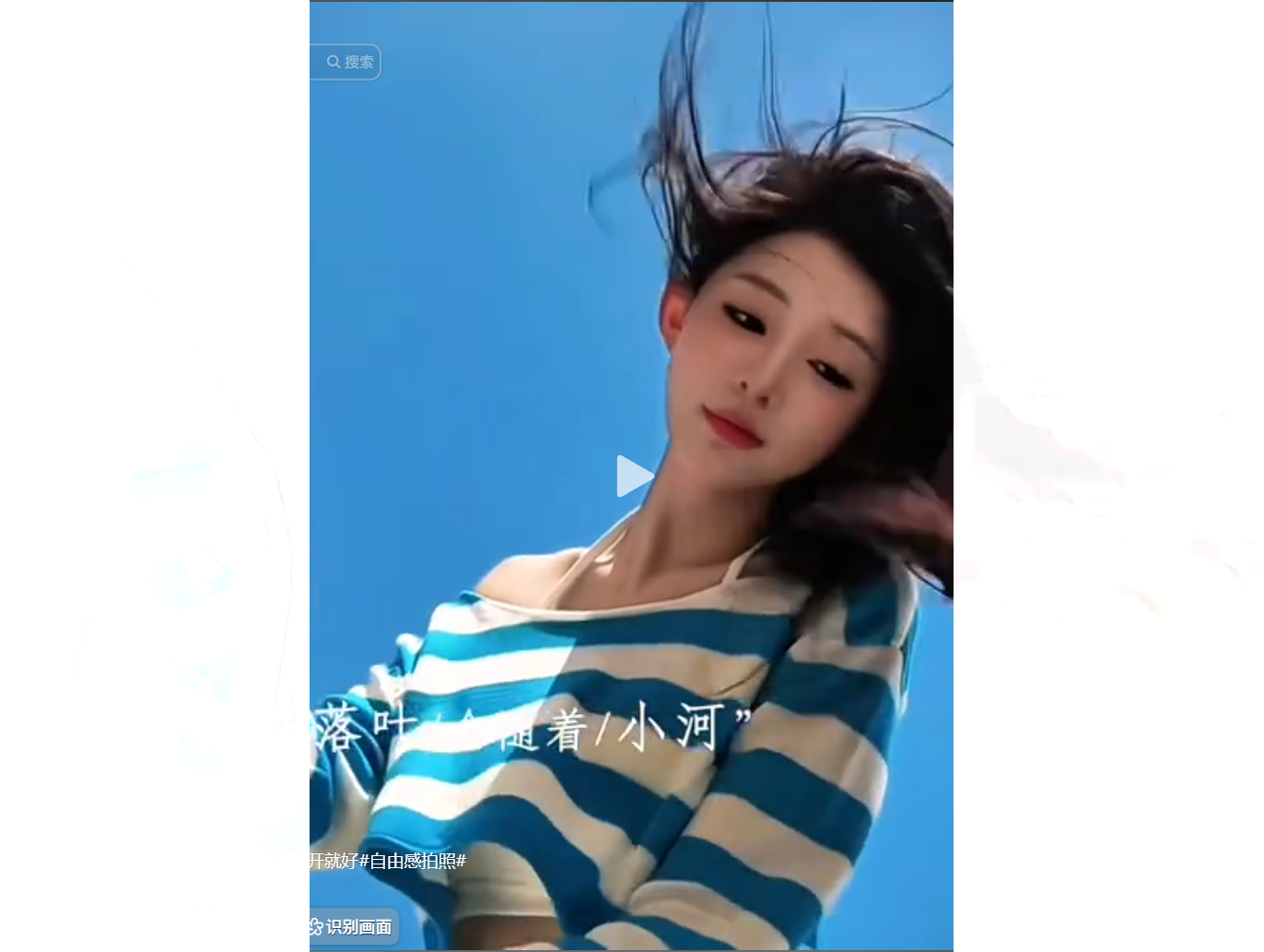 女子穿藍白條紋上衣，頭髮隨風飄揚，背景為藍天。