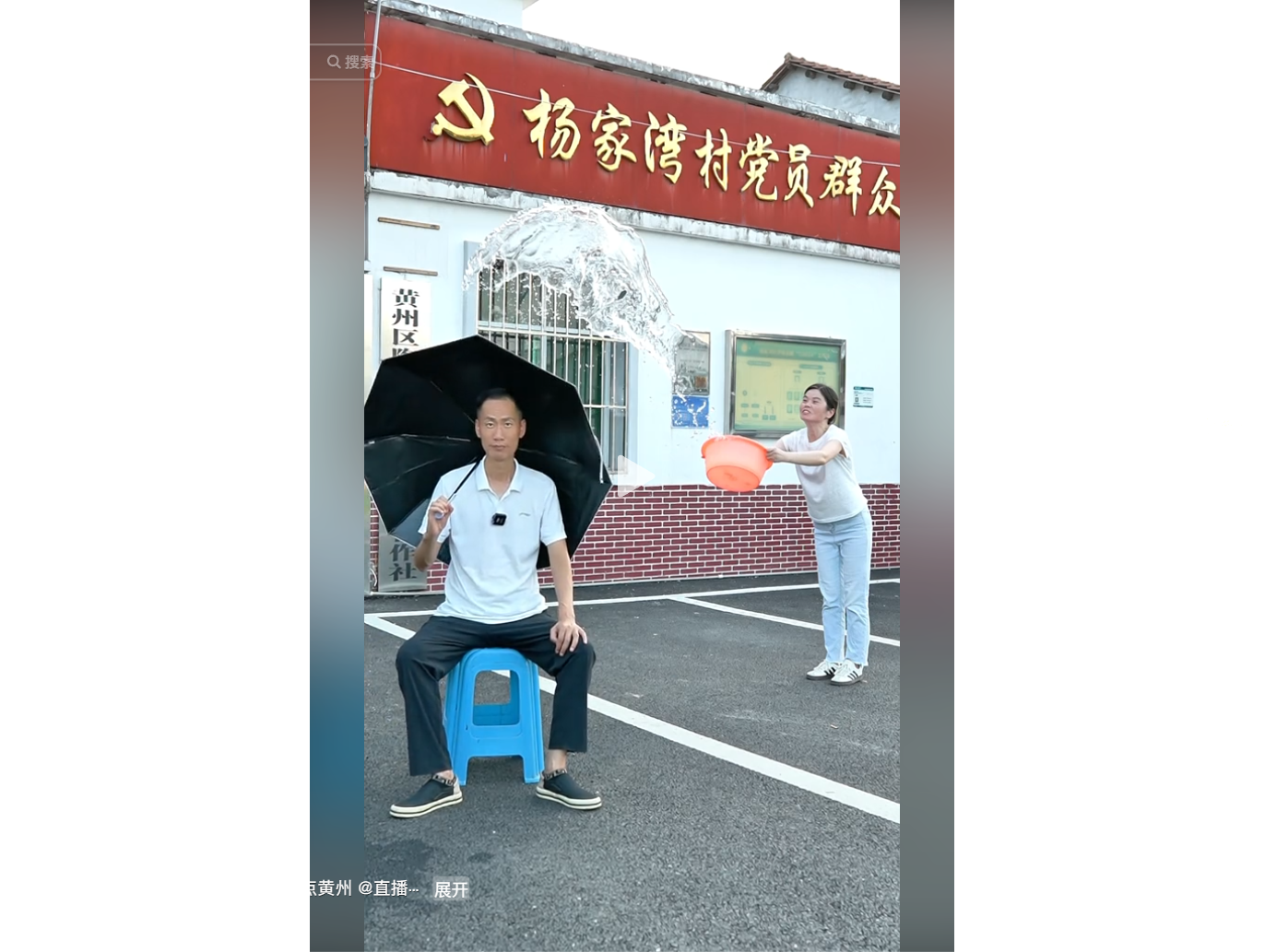 女子向持傘男子潑水，背景為村黨員群眾服務中心