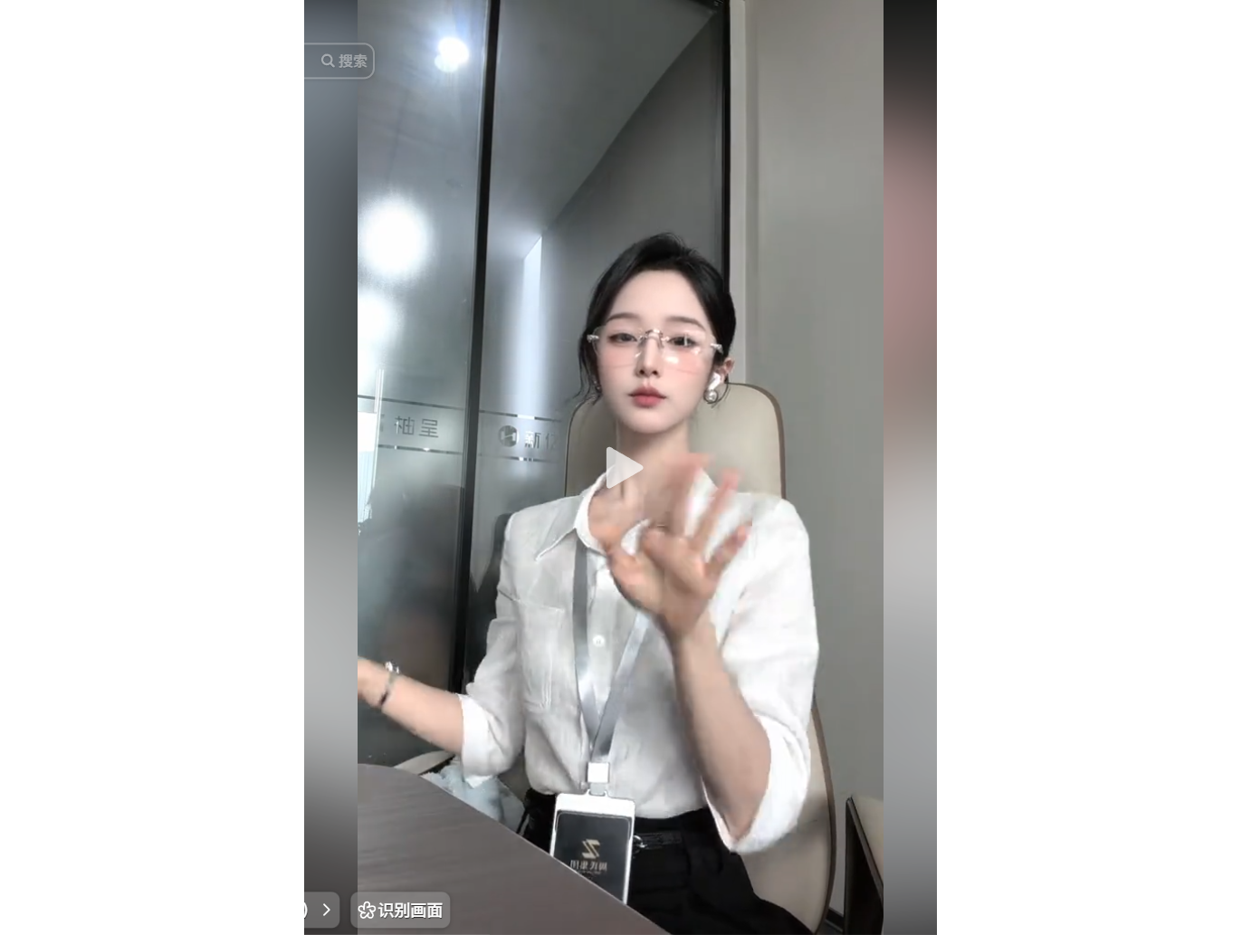 A woman in a white shirt and glasses sits at a des